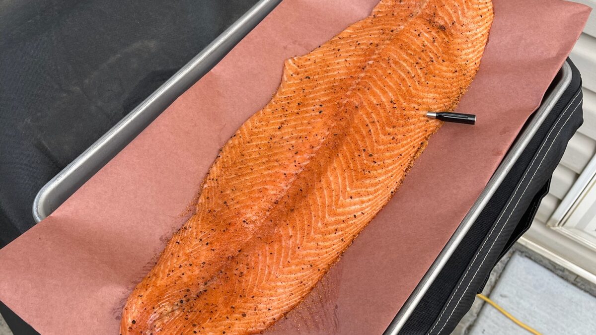 Full side of smoked salmon with a deep orange glaze resting on pink butcher paper