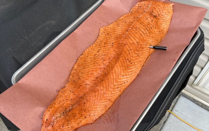 Full side of smoked salmon with a deep orange glaze resting on pink butcher paper