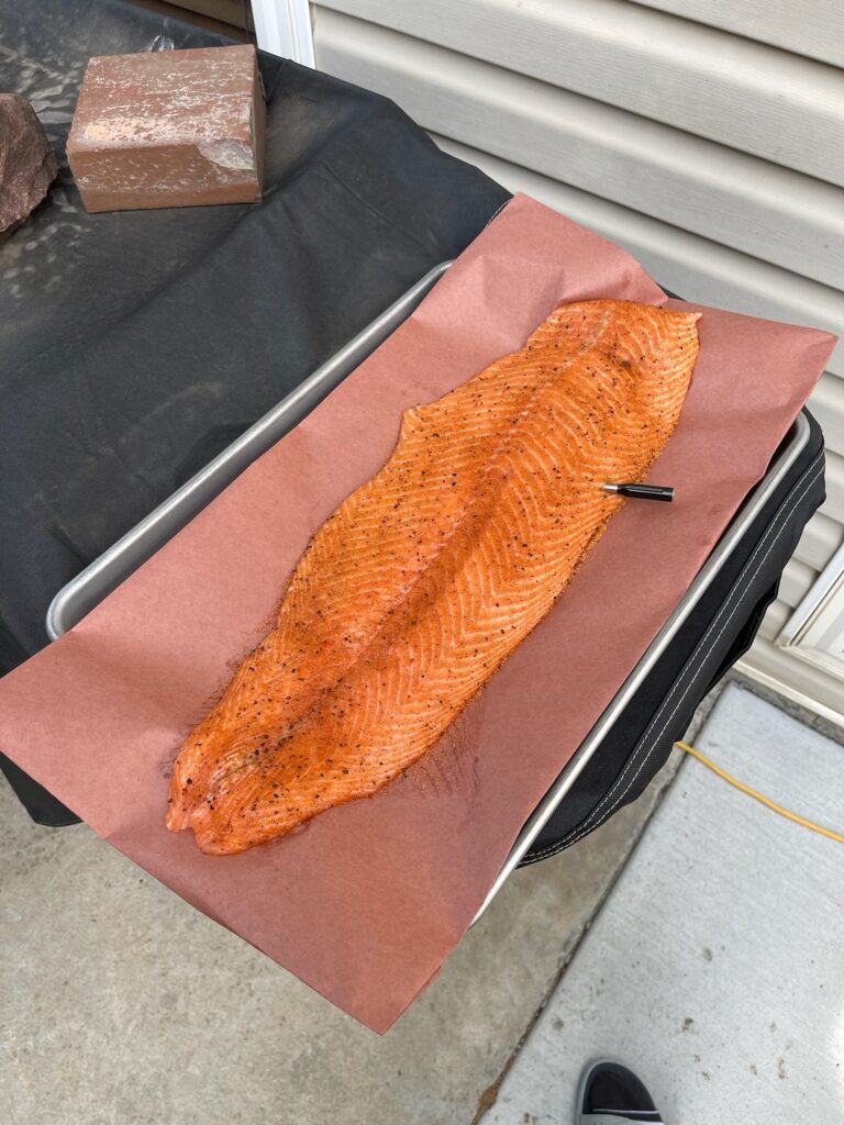 Full side of smoked salmon with a deep orange glaze resting on pink butcher paper