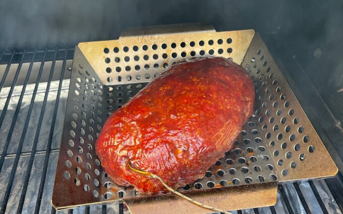Smoked meatloaf with a deep red glaze on the smoker grates